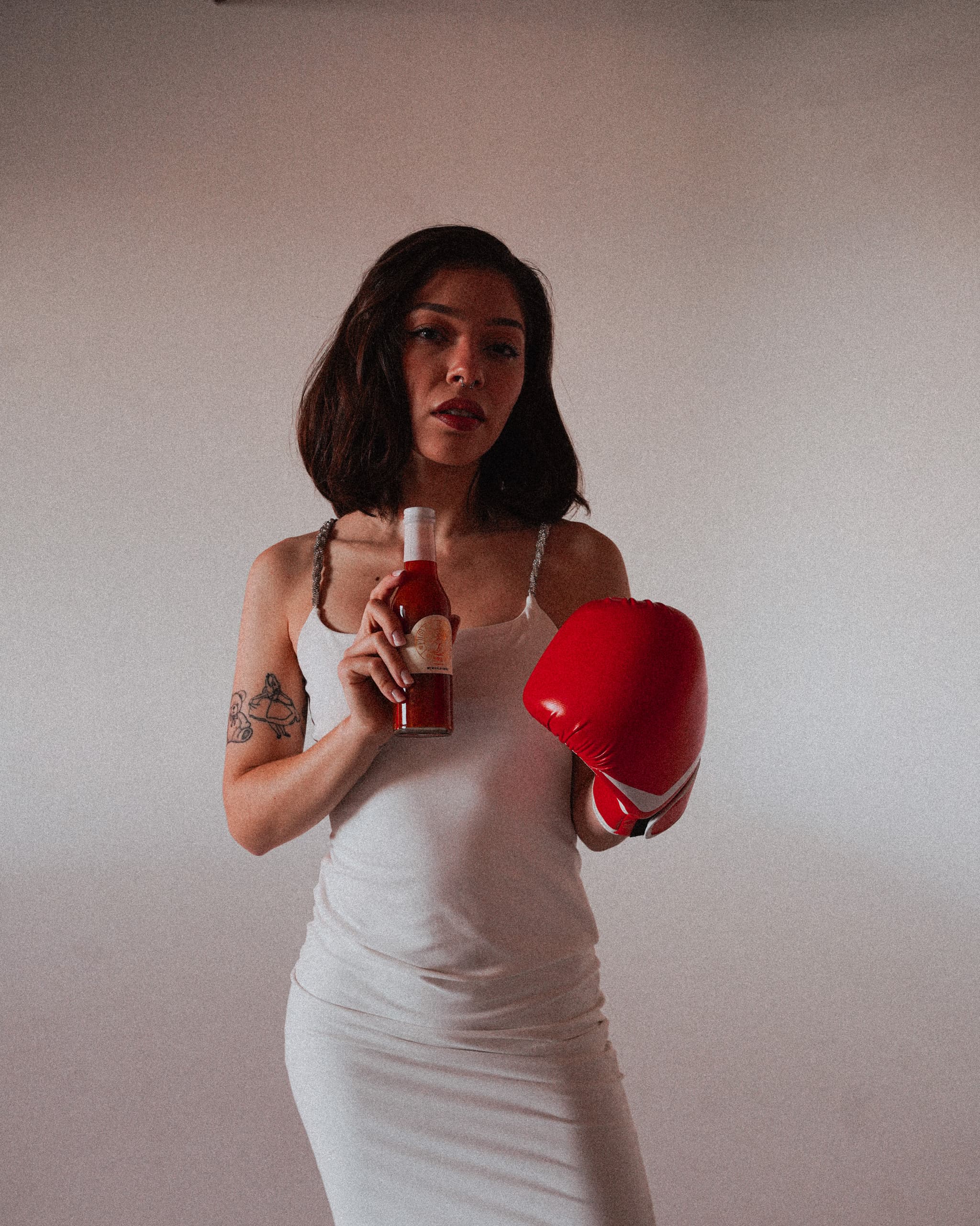 Alyssa in a white dress with a red boxing glove and a 1971 Hook bottle