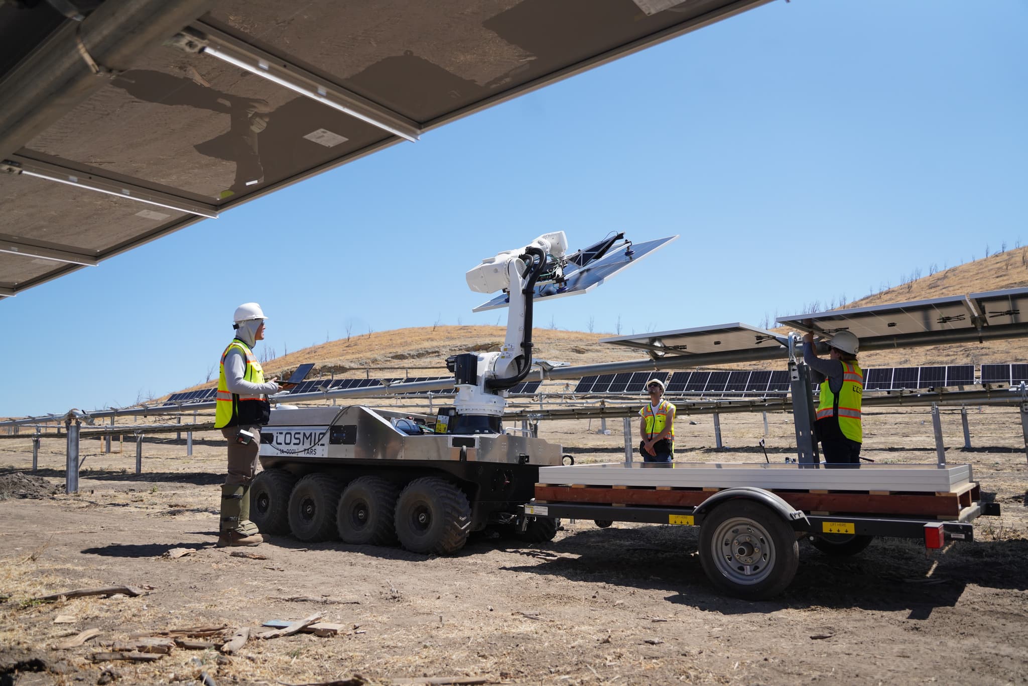Wide view of the Patterson, California solar field with the robot and crew mid-installation