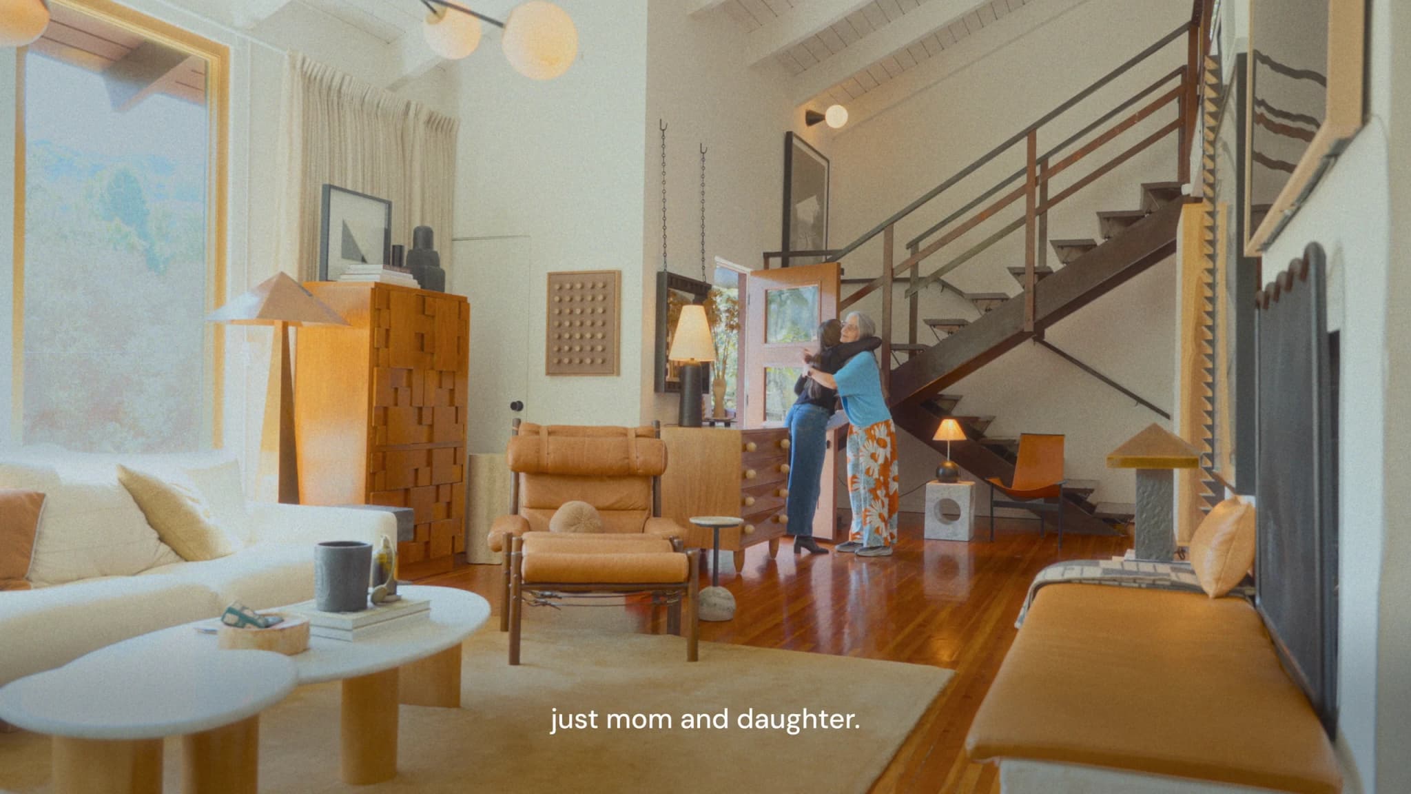 Wide living-room frame of mother and daughter embracing, with the subtitle just mom and daughter